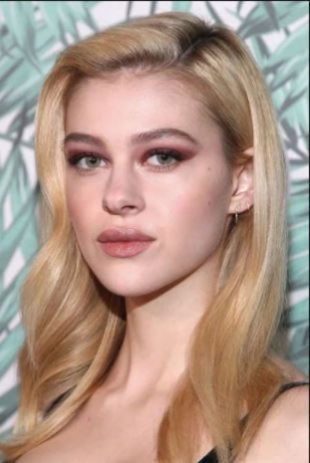 Nicola Peltz in a black top poses at a photoshoot.